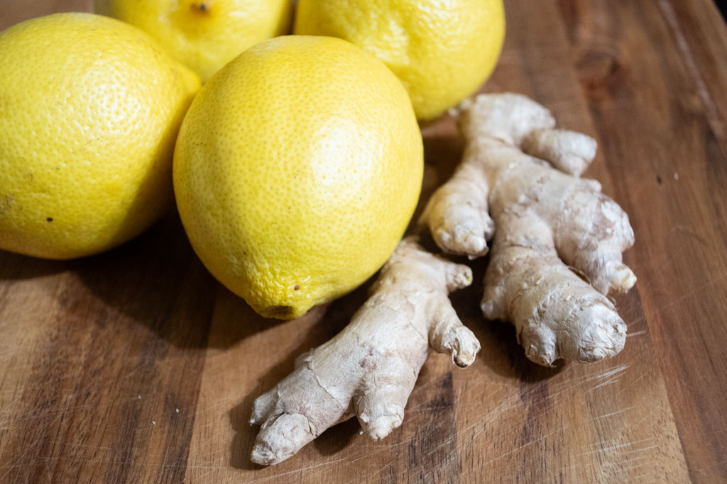 Whole Lemons and ginger root on a wood cutting board